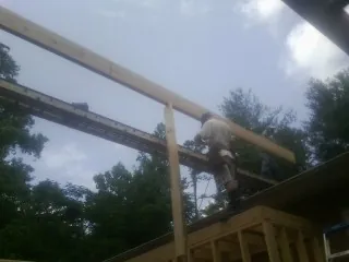 Carpenter setting a ridge beam over a new addition frame — Ice Dam Removal by Roofing Brothers in Clint