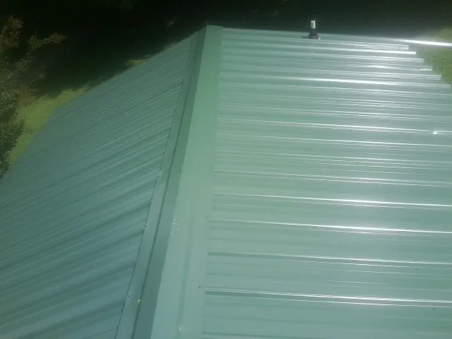 New green metal panels meeting at the ridge of a roof — Flat Roof Repair work by our crew in Clint