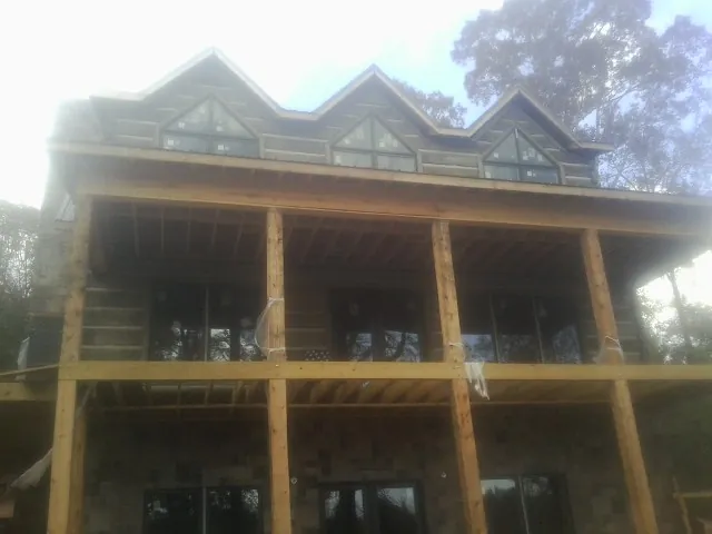 Dormers and porch framing on a large log home under construction — Roof Coating work by our crew in Clint