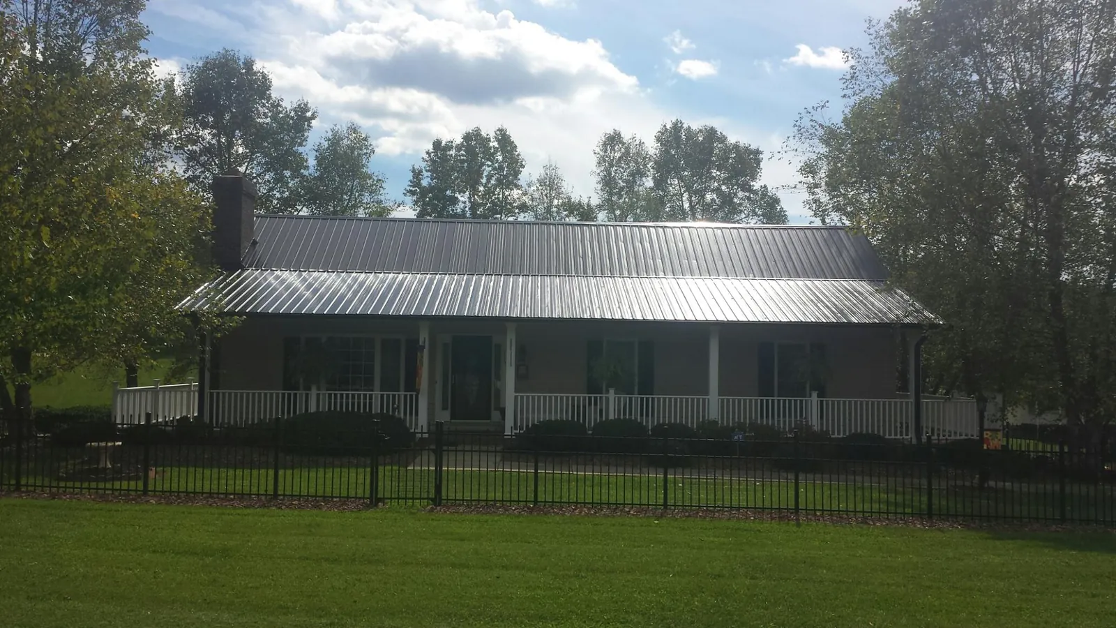 Gray metal roof on a brick ranch with a full width front porch — Gutter Guard Installation work by our crew in Clint