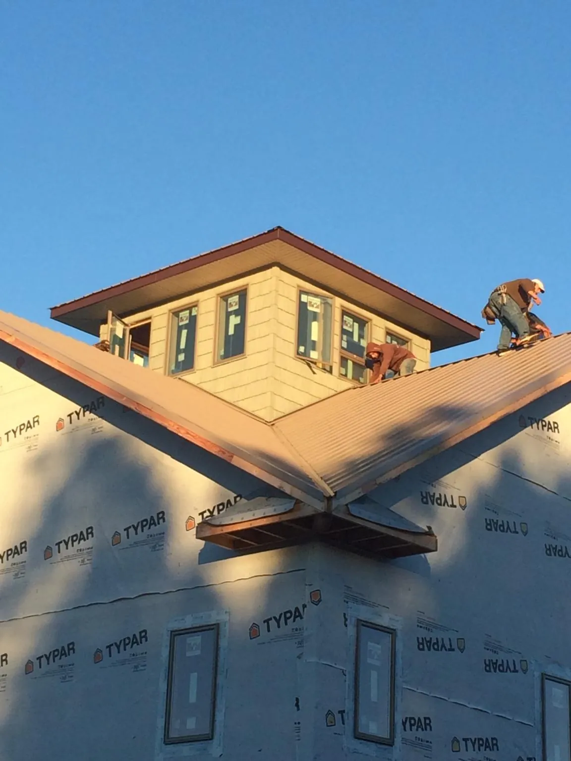 Roofers working around a rooftop cupola on a new metal roof at sunset — Roof Waterproofing in Clint by Roofing Brothers
